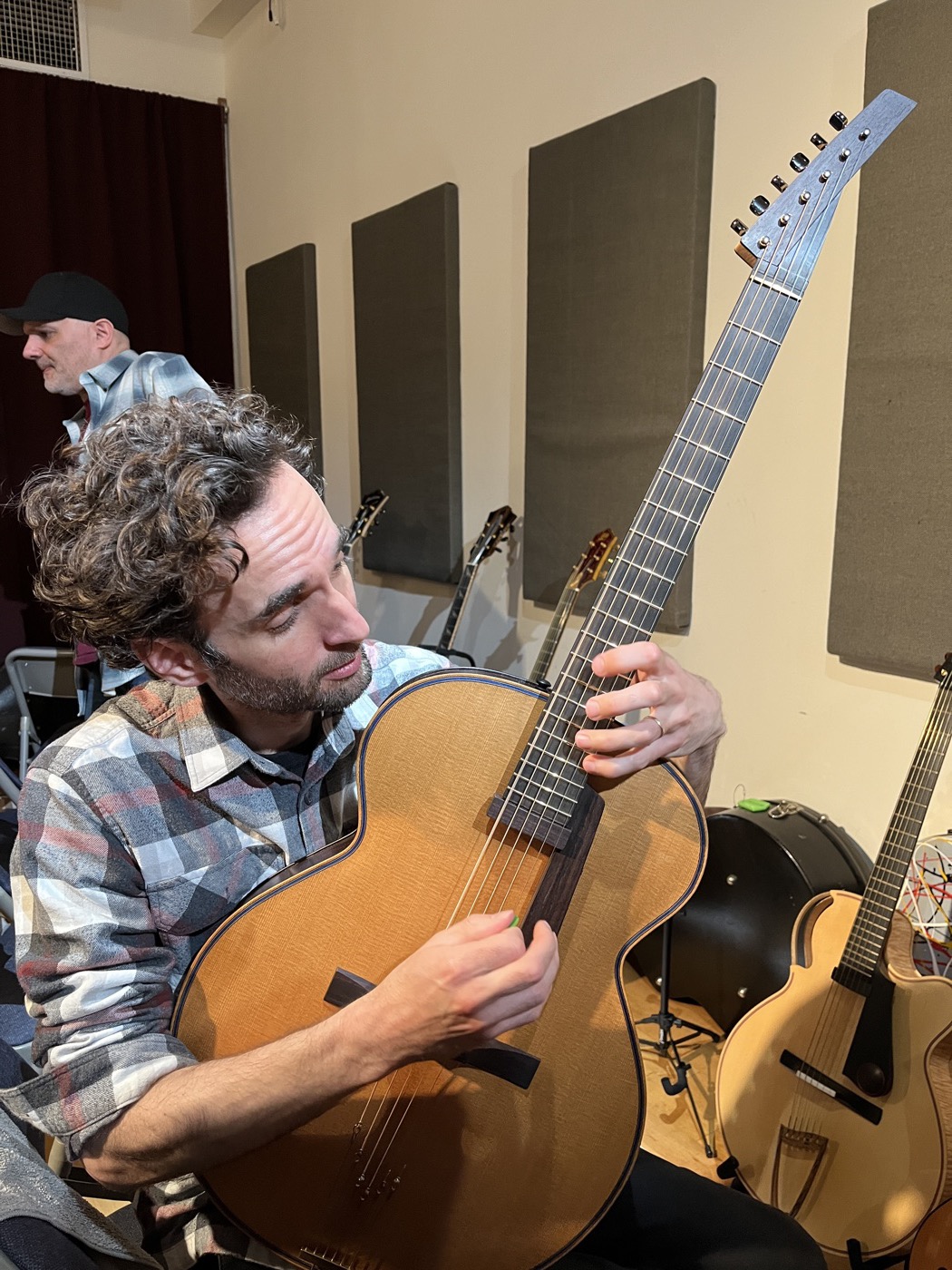 A player seated among guitar cases and instruments in a previous Feast room.