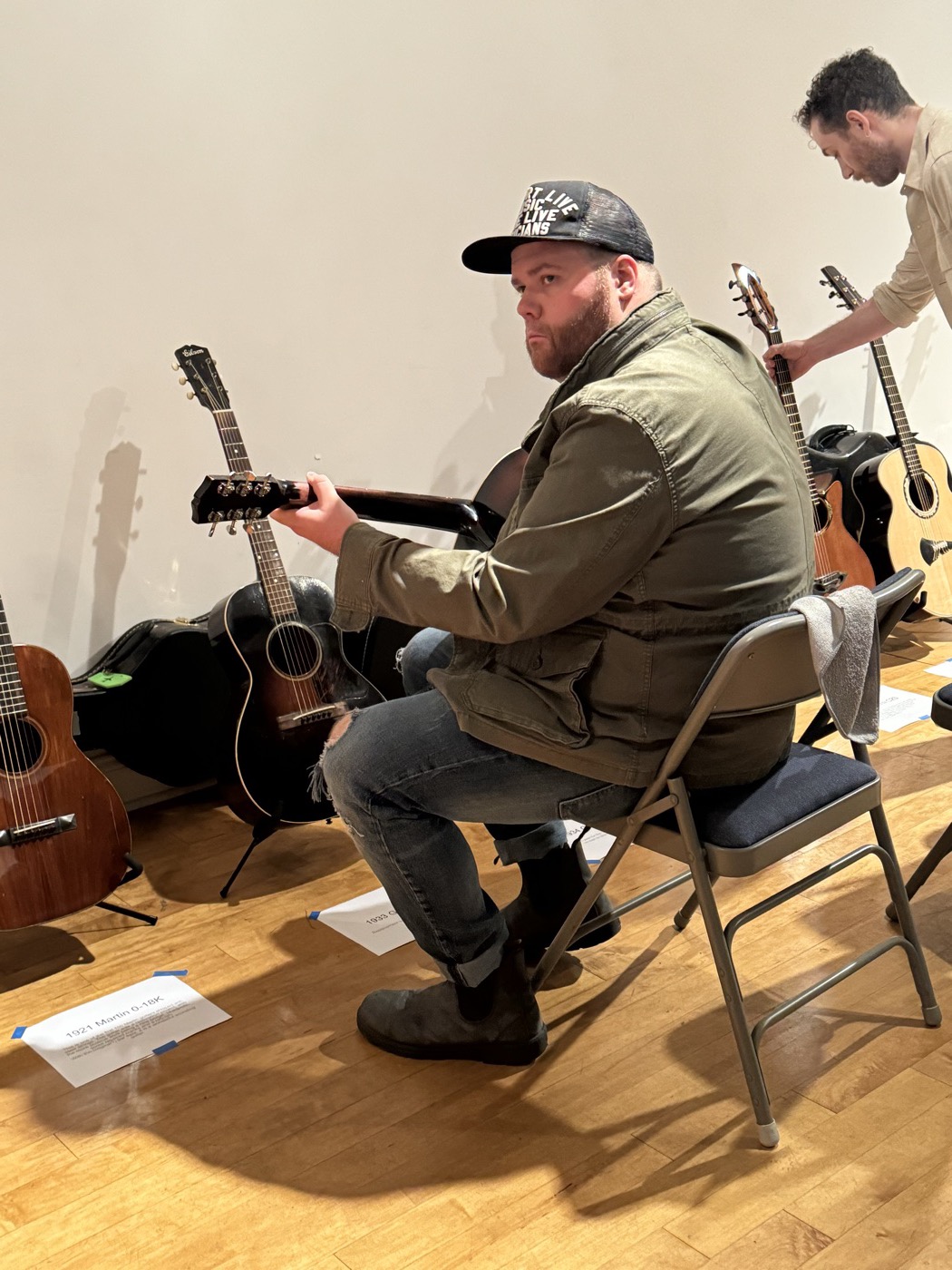 A player seated among instruments and cases in a previous event room.