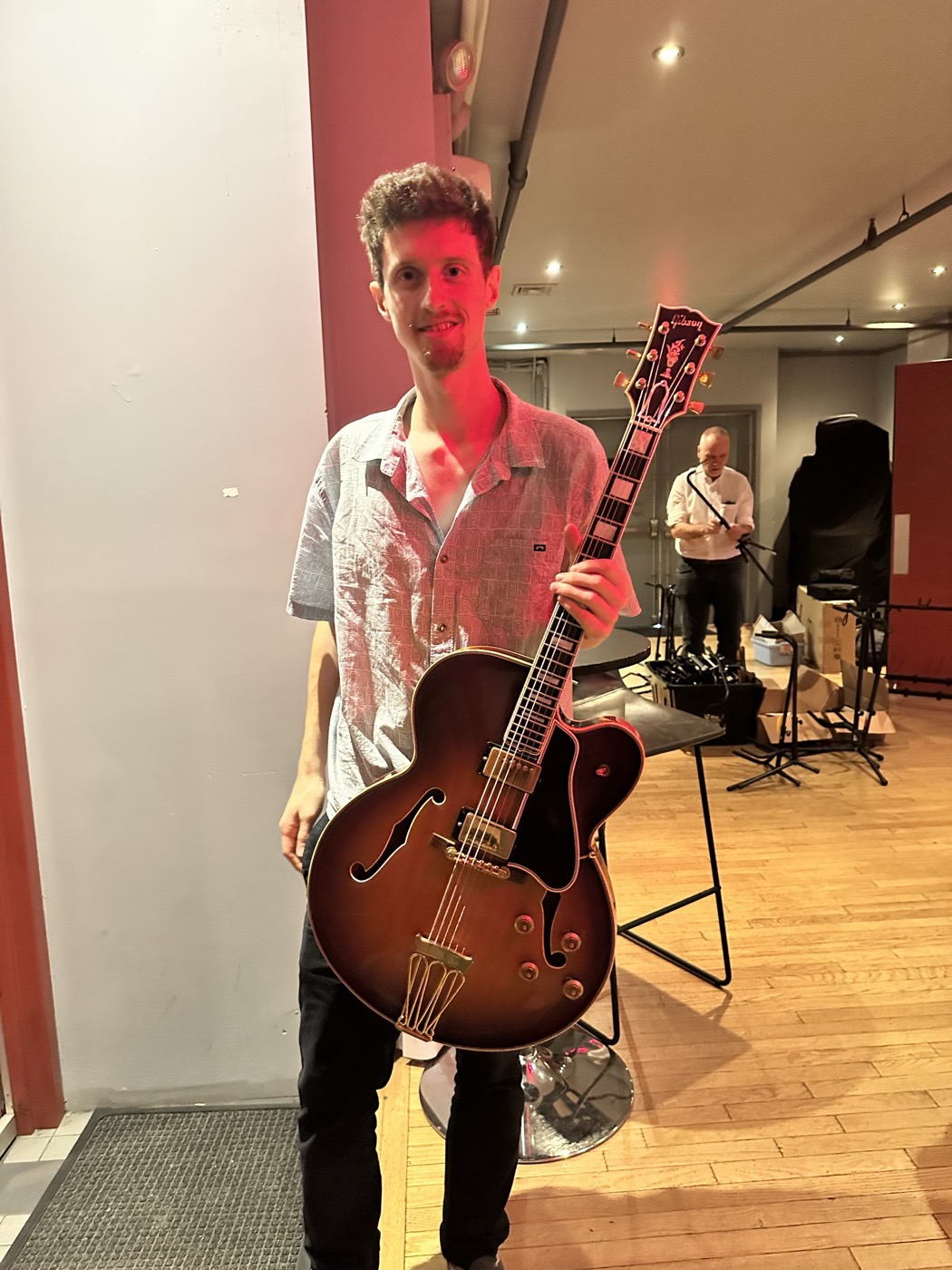 An attendee standing with a sunburst archtop guitar.