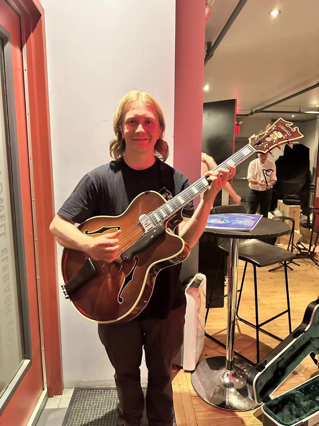 An attendee standing with a vintage-style archtop guitar.